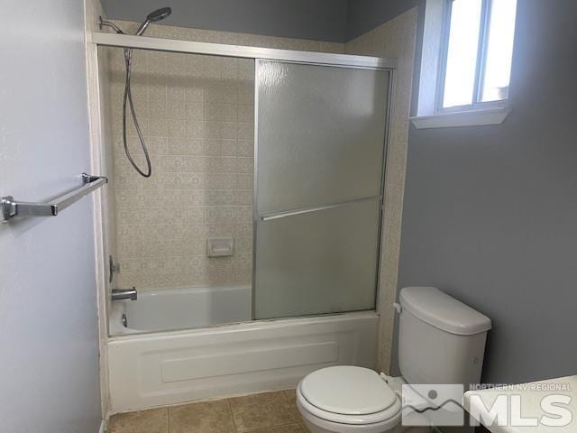 bathroom with tile patterned floors, toilet, and combined bath / shower with glass door