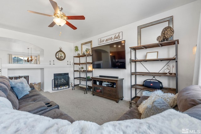 carpeted living room with ceiling fan with notable chandelier