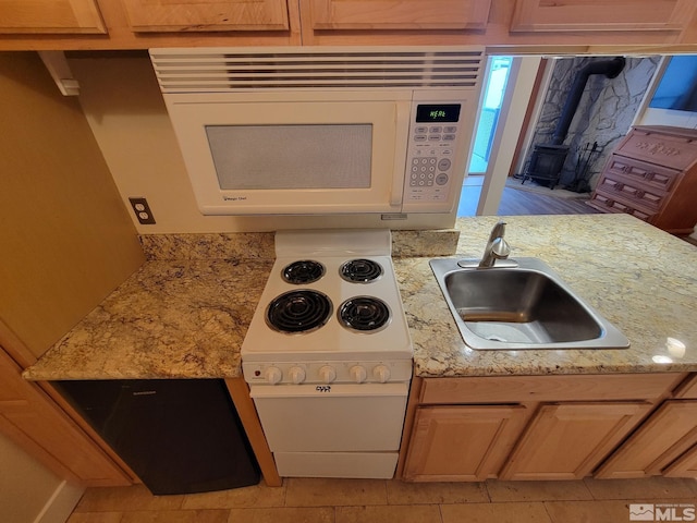 kitchen with light brown cabinets, a wood stove, sink, and white microwave