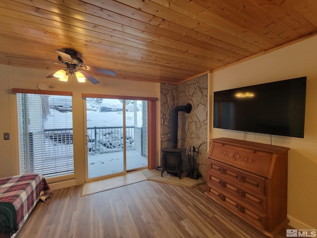 unfurnished living room featuring hardwood / wood-style floors, a wood stove, ceiling fan, and wood ceiling