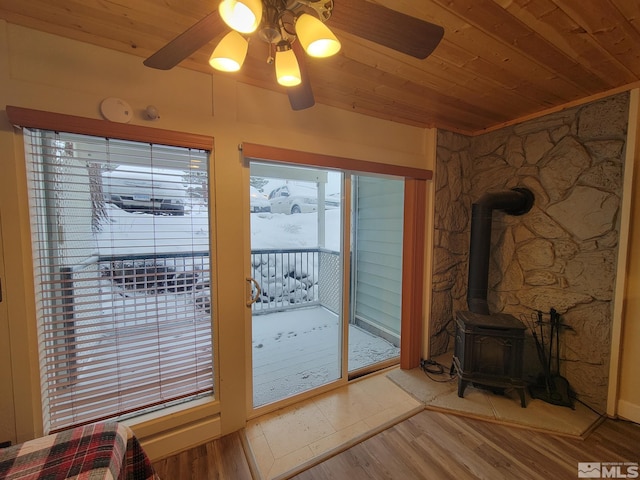 doorway to outside with a wood stove, hardwood / wood-style flooring, ceiling fan, a healthy amount of sunlight, and wood ceiling