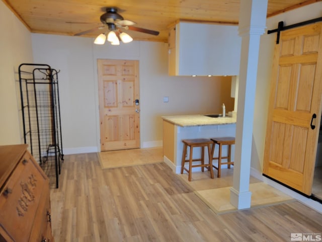 kitchen featuring a kitchen bar, ceiling fan, sink, wooden ceiling, and light hardwood / wood-style floors