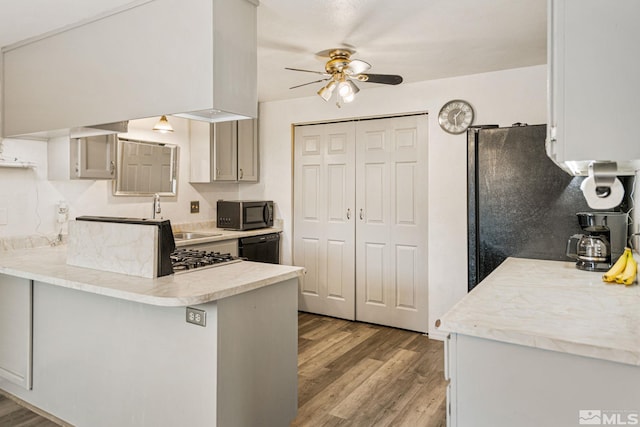 kitchen with kitchen peninsula, sink, black appliances, light hardwood / wood-style flooring, and gray cabinets