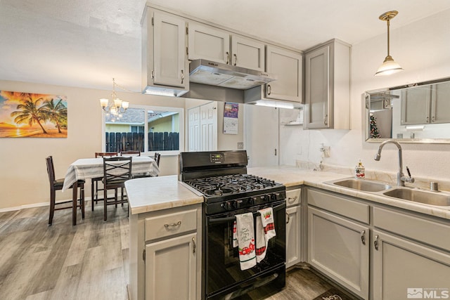 kitchen featuring sink, decorative light fixtures, a notable chandelier, gas stove, and kitchen peninsula