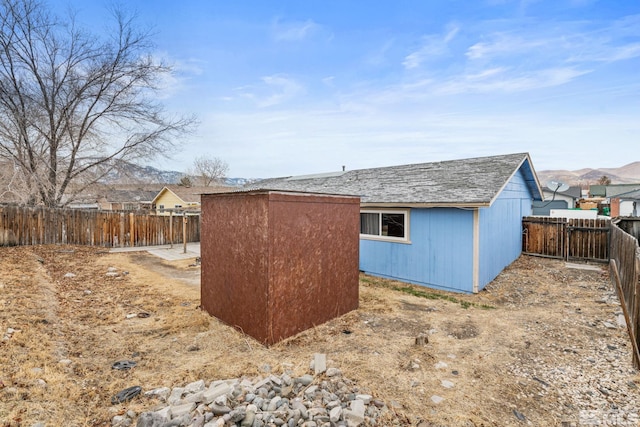 view of side of home with a mountain view and a storage shed