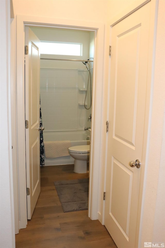 bathroom featuring hardwood / wood-style flooring, toilet, and shower / bath combo with shower curtain