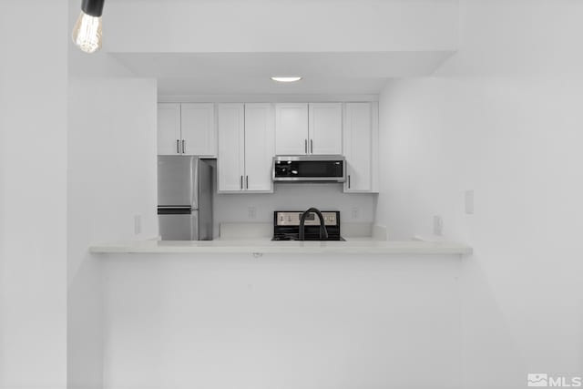 room details featuring white cabinetry, sink, and appliances with stainless steel finishes