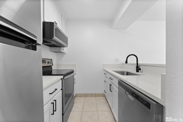 kitchen featuring white cabinets, appliances with stainless steel finishes, light tile patterned flooring, and sink