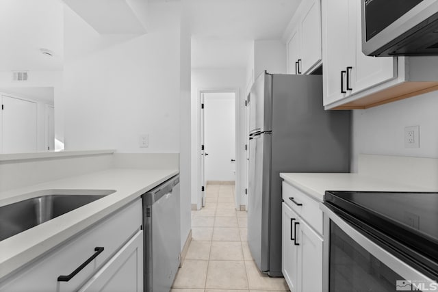 kitchen with white cabinets, light tile patterned flooring, and appliances with stainless steel finishes