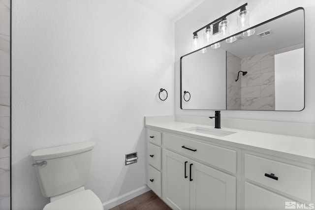 bathroom with tiled shower, vanity, and toilet