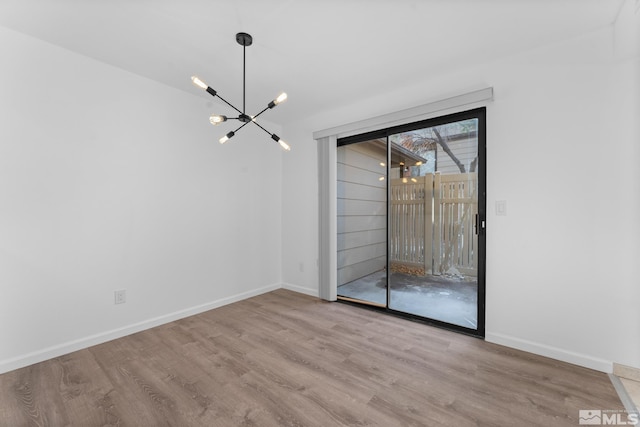 unfurnished room featuring an inviting chandelier and light hardwood / wood-style flooring