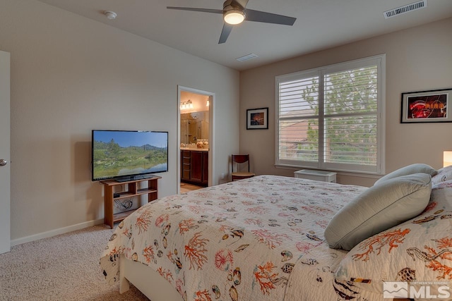 carpeted bedroom featuring multiple windows, ensuite bath, and ceiling fan