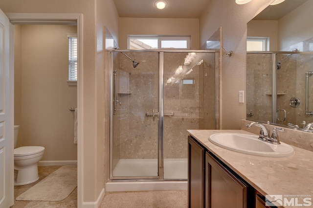 bathroom featuring walk in shower, vanity, toilet, and a wealth of natural light