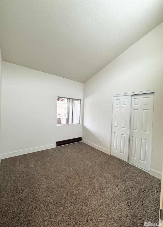 carpeted spare room featuring a baseboard radiator and lofted ceiling