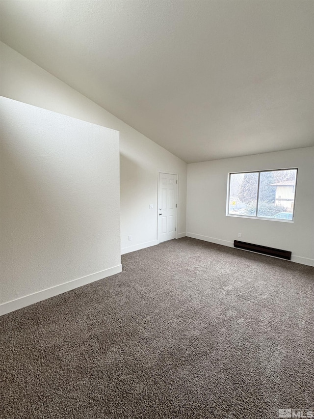 empty room featuring lofted ceiling, carpet floors, and a baseboard heating unit