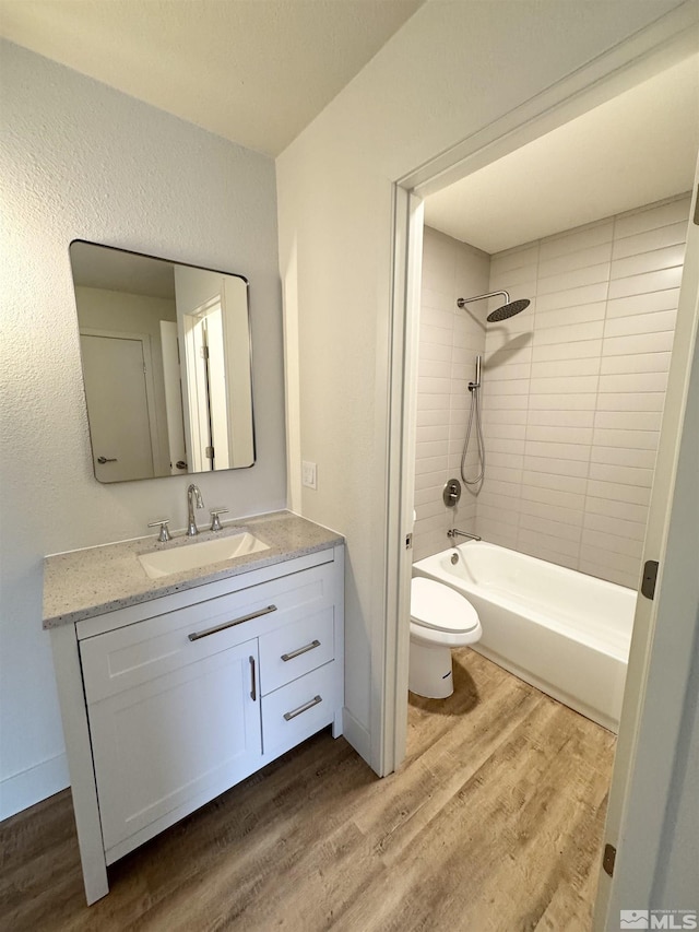 full bathroom with wood-type flooring, vanity, toilet, and tiled shower / bath