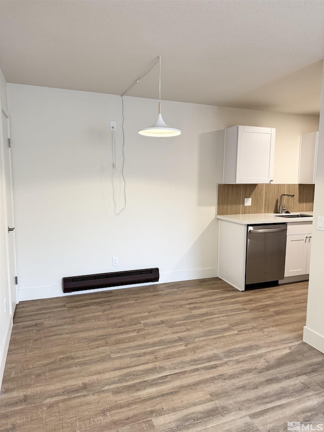 kitchen featuring tasteful backsplash, stainless steel dishwasher, baseboard heating, decorative light fixtures, and white cabinets