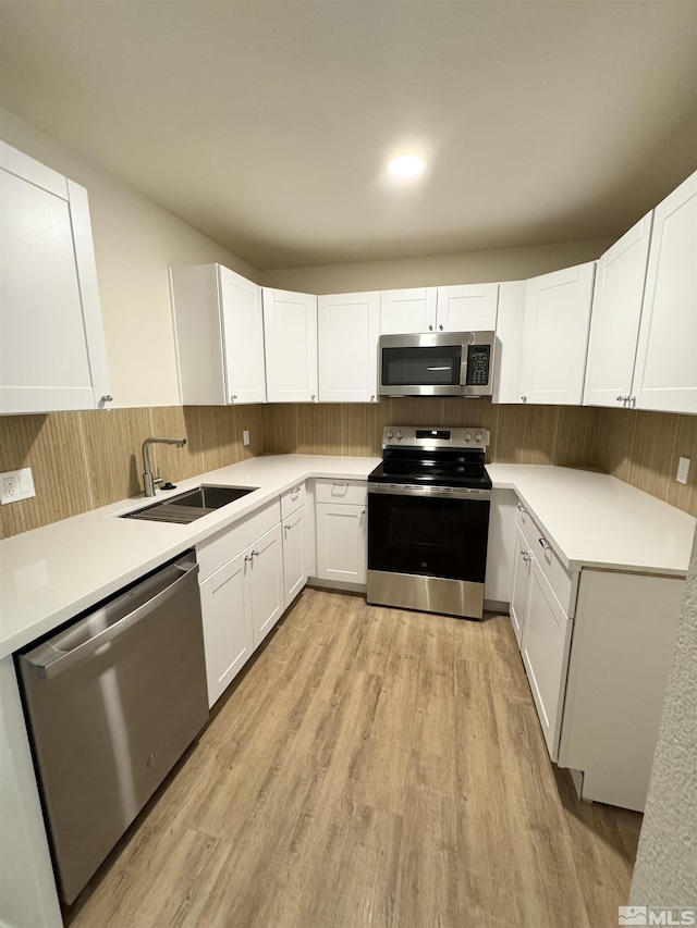 kitchen featuring white cabinets, light hardwood / wood-style floors, sink, and stainless steel appliances