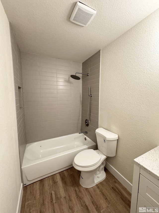 full bathroom with toilet, tiled shower / bath, a textured ceiling, and hardwood / wood-style flooring