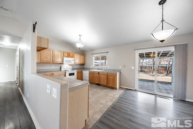 kitchen featuring kitchen peninsula, pendant lighting, lofted ceiling, white appliances, and light brown cabinetry