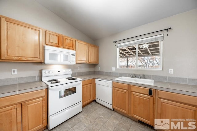 kitchen with vaulted ceiling, tile countertops, sink, and white appliances