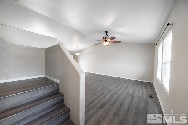 stairs featuring ceiling fan, wood-type flooring, and vaulted ceiling