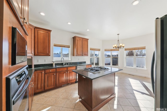 kitchen featuring a center island, sink, appliances with stainless steel finishes, light tile patterned flooring, and a chandelier