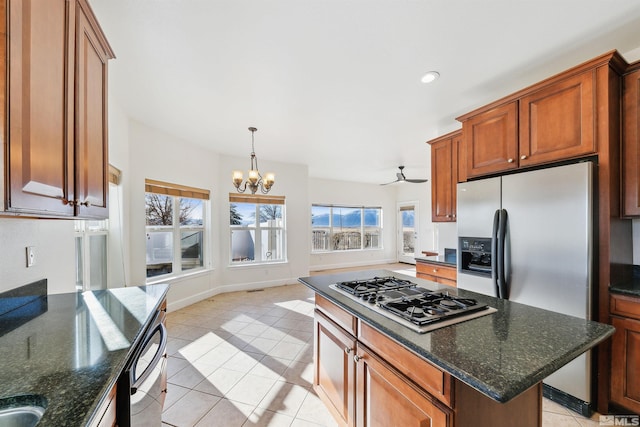 kitchen featuring ceiling fan with notable chandelier, dark stone countertops, light tile patterned floors, and stainless steel appliances