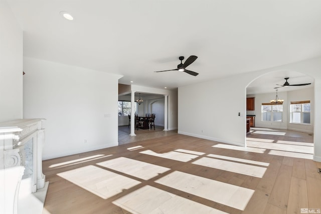 unfurnished living room featuring ceiling fan with notable chandelier and hardwood / wood-style flooring