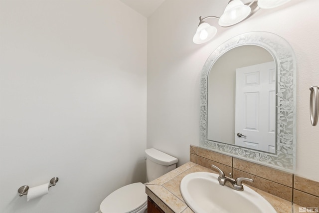 bathroom featuring vanity, toilet, and backsplash