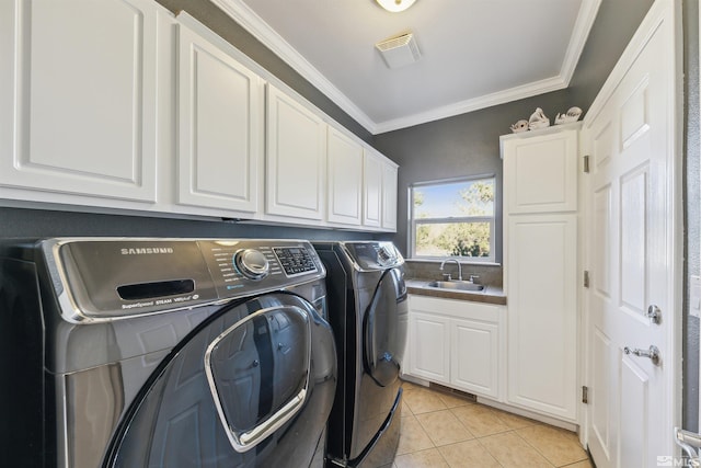 washroom featuring cabinets, crown molding, sink, light tile patterned floors, and washing machine and clothes dryer