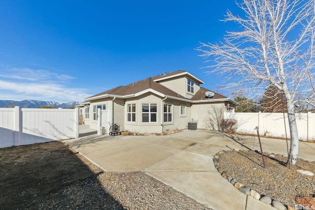 back of property featuring a mountain view, a patio, and central AC