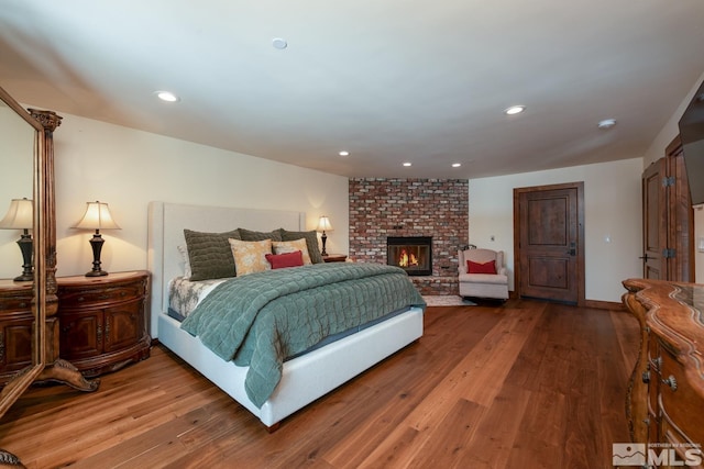 bedroom with a brick fireplace and hardwood / wood-style flooring