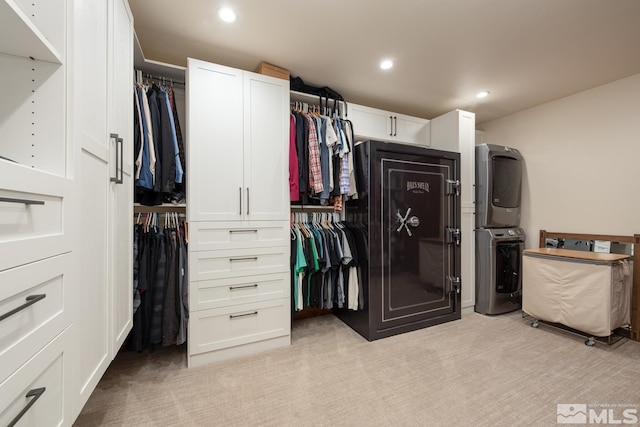 walk in closet featuring stacked washer and dryer and light colored carpet