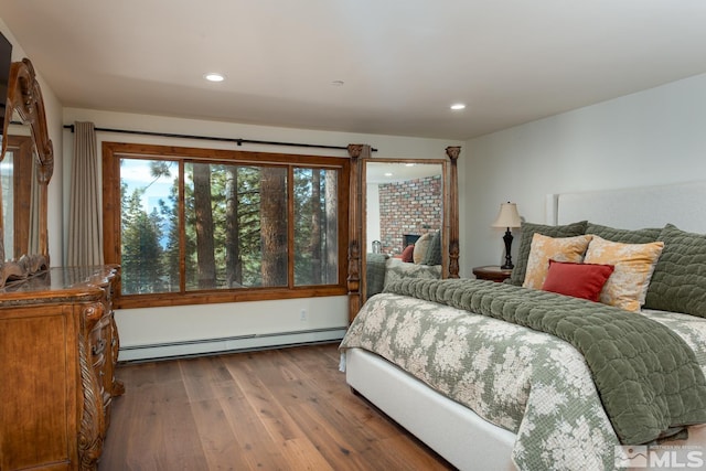 bedroom featuring hardwood / wood-style floors, a brick fireplace, and a baseboard radiator