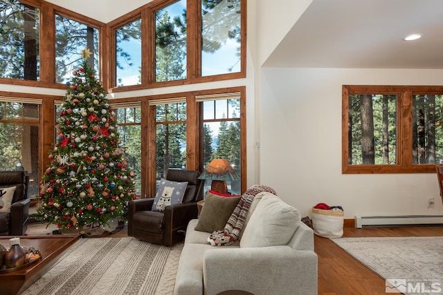 living room featuring hardwood / wood-style floors, a high ceiling, and a baseboard radiator