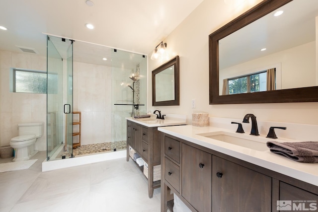 bathroom featuring vanity, toilet, and a shower with shower door