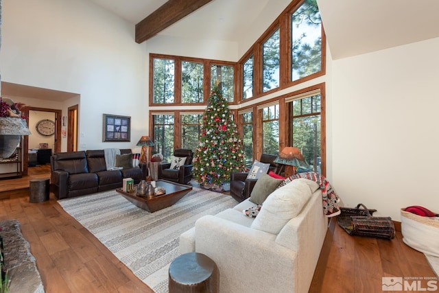 living room featuring beamed ceiling, a high ceiling, and hardwood / wood-style flooring