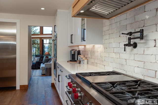 kitchen featuring decorative backsplash, premium range hood, premium appliances, dark hardwood / wood-style floors, and white cabinetry