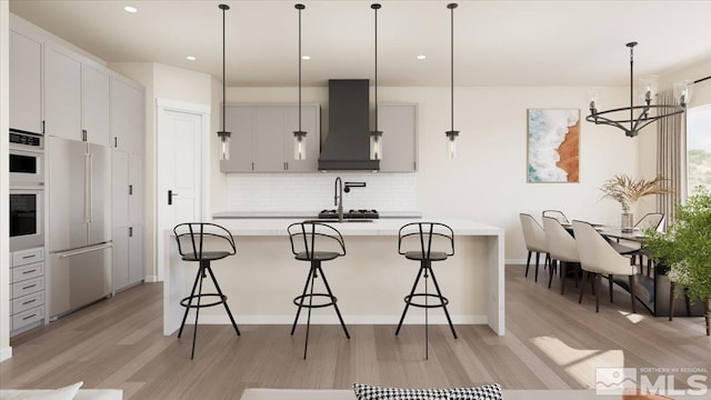 kitchen featuring backsplash, premium range hood, high quality fridge, a breakfast bar, and hanging light fixtures