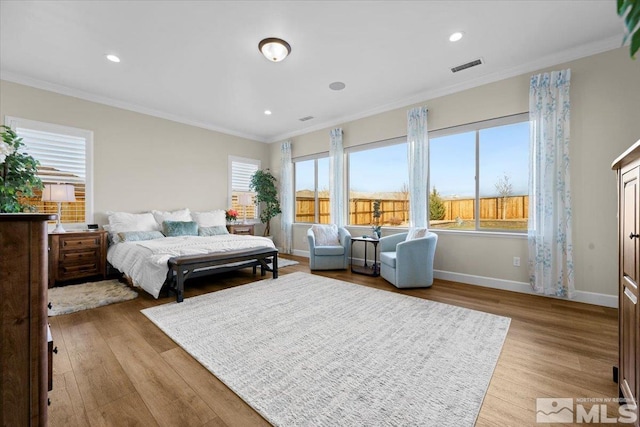 bedroom featuring light hardwood / wood-style floors, ornamental molding, and multiple windows