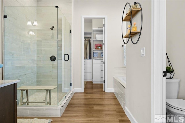 bathroom with hardwood / wood-style floors, separate shower and tub, and toilet