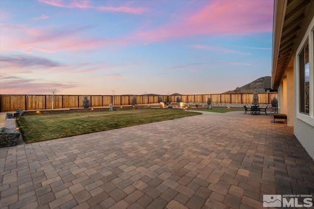 patio terrace at dusk featuring a yard