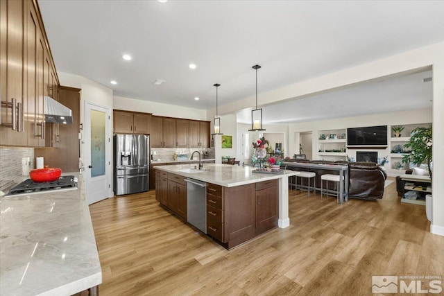 kitchen featuring light stone countertops, stainless steel appliances, sink, hanging light fixtures, and a large island