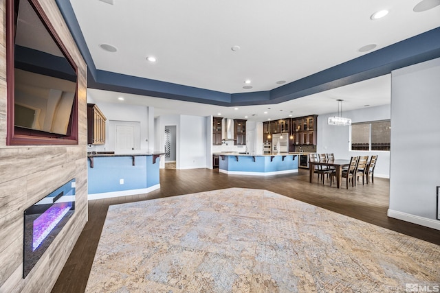 interior space with pendant lighting, a tile fireplace, a kitchen breakfast bar, a spacious island, and stainless steel refrigerator with ice dispenser