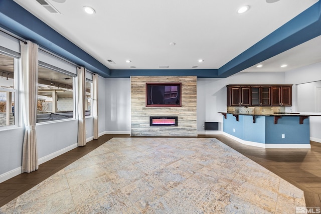 unfurnished living room with a tile fireplace, a wealth of natural light, and dark wood-type flooring