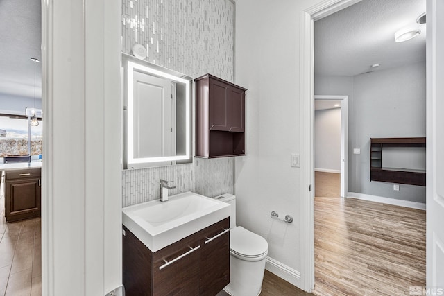 bathroom featuring vanity, backsplash, hardwood / wood-style flooring, toilet, and a textured ceiling