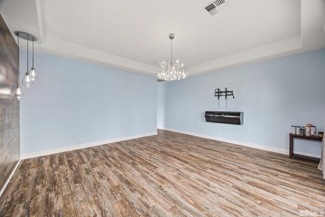 unfurnished room featuring hardwood / wood-style flooring, a notable chandelier, and a tray ceiling