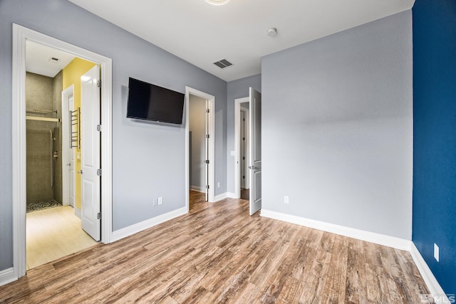 unfurnished bedroom with light hardwood / wood-style floors and ensuite bath