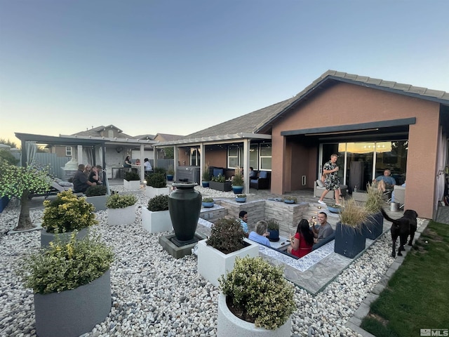 back house at dusk featuring an outdoor living space and a patio area